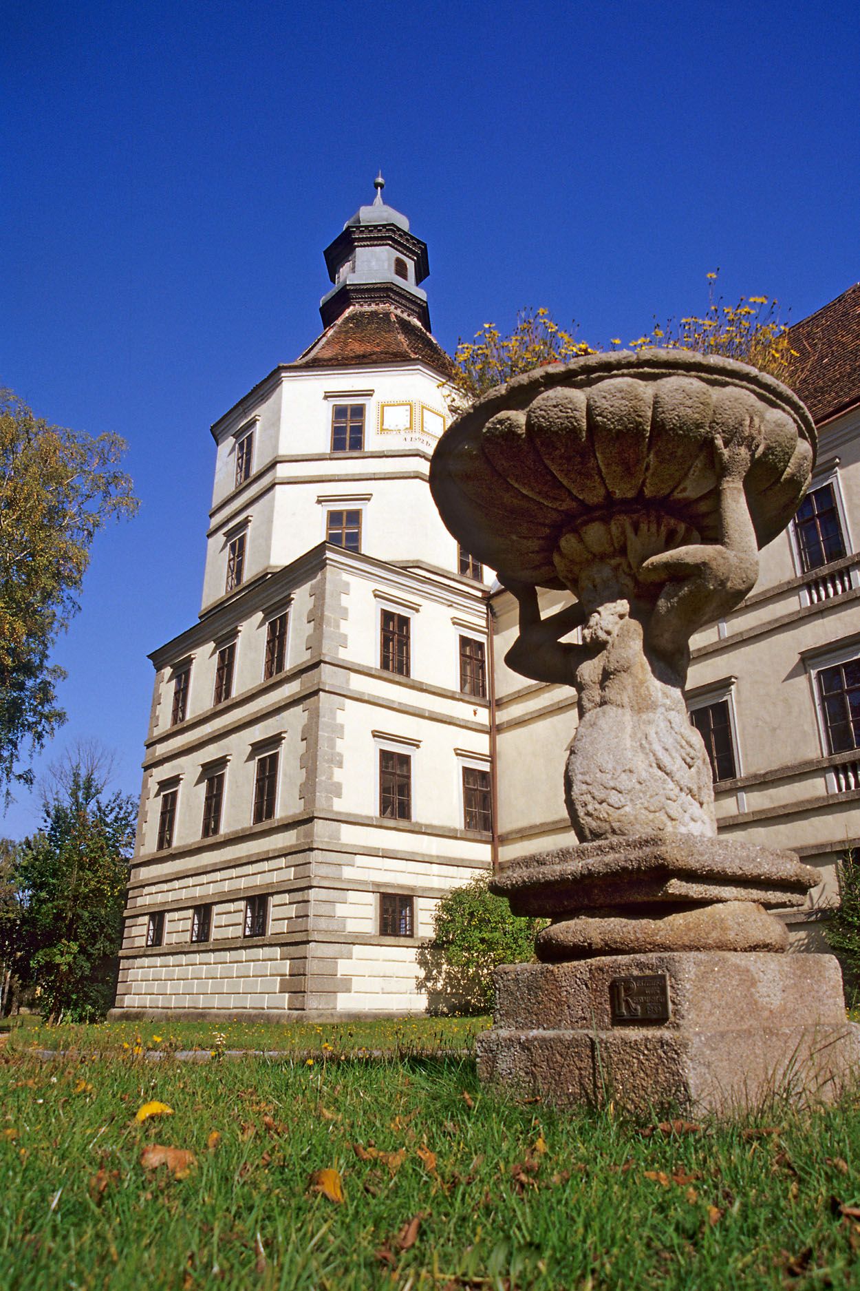 Ein historisches Gebäude mit Turm und eine steinerne Statue im Vordergrund.