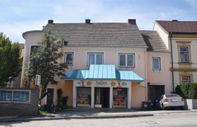 Ein kleines Restaurant mit blauer Markise und einem Auto davor.