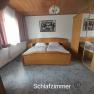 Schlafzimmer mit Doppelbett, Holzmöbeln und Spiegel.