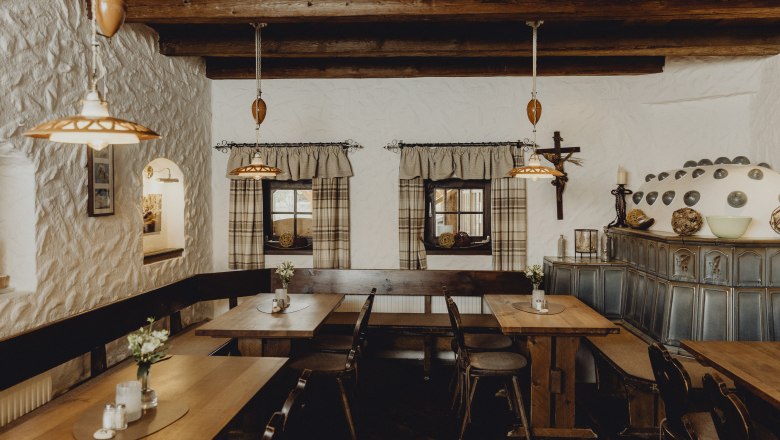 Gemütliche Stube mit Holzmöbeln, Kachelofen und rustikaler Dekoration.