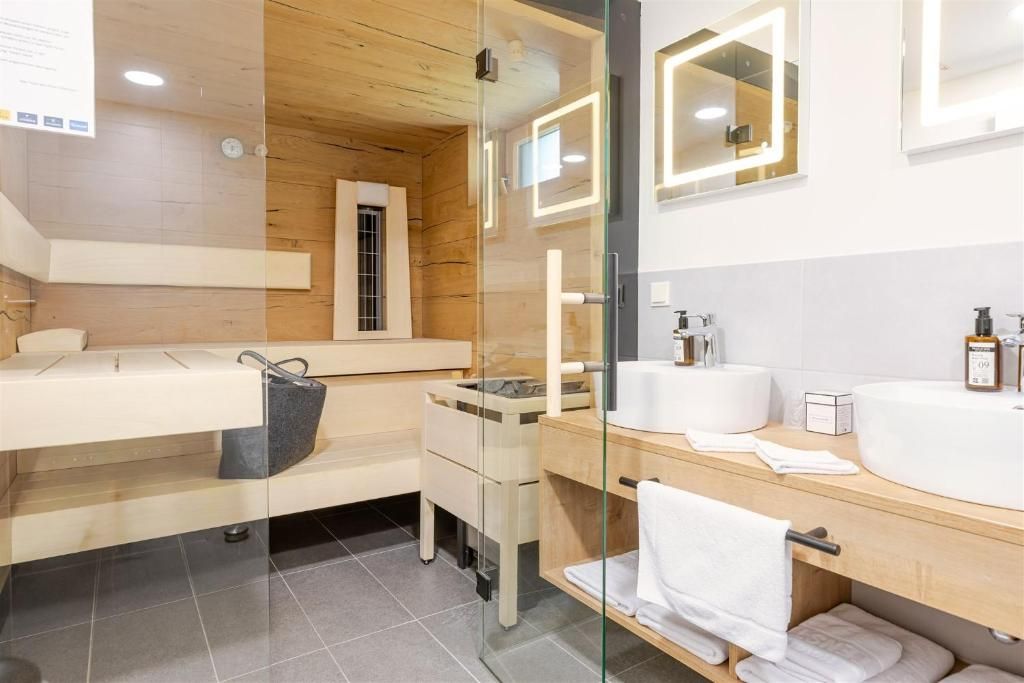 Modernes Hotelbad im Hotel Ottenstein mit Holzoptik, Glasdusche, Doppelwaschbecken und Sauna.