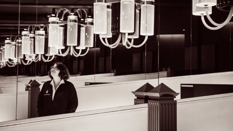 Eine Frau steht in einem Raum mit großen, modernen Kronleuchtern und Spiegeln.