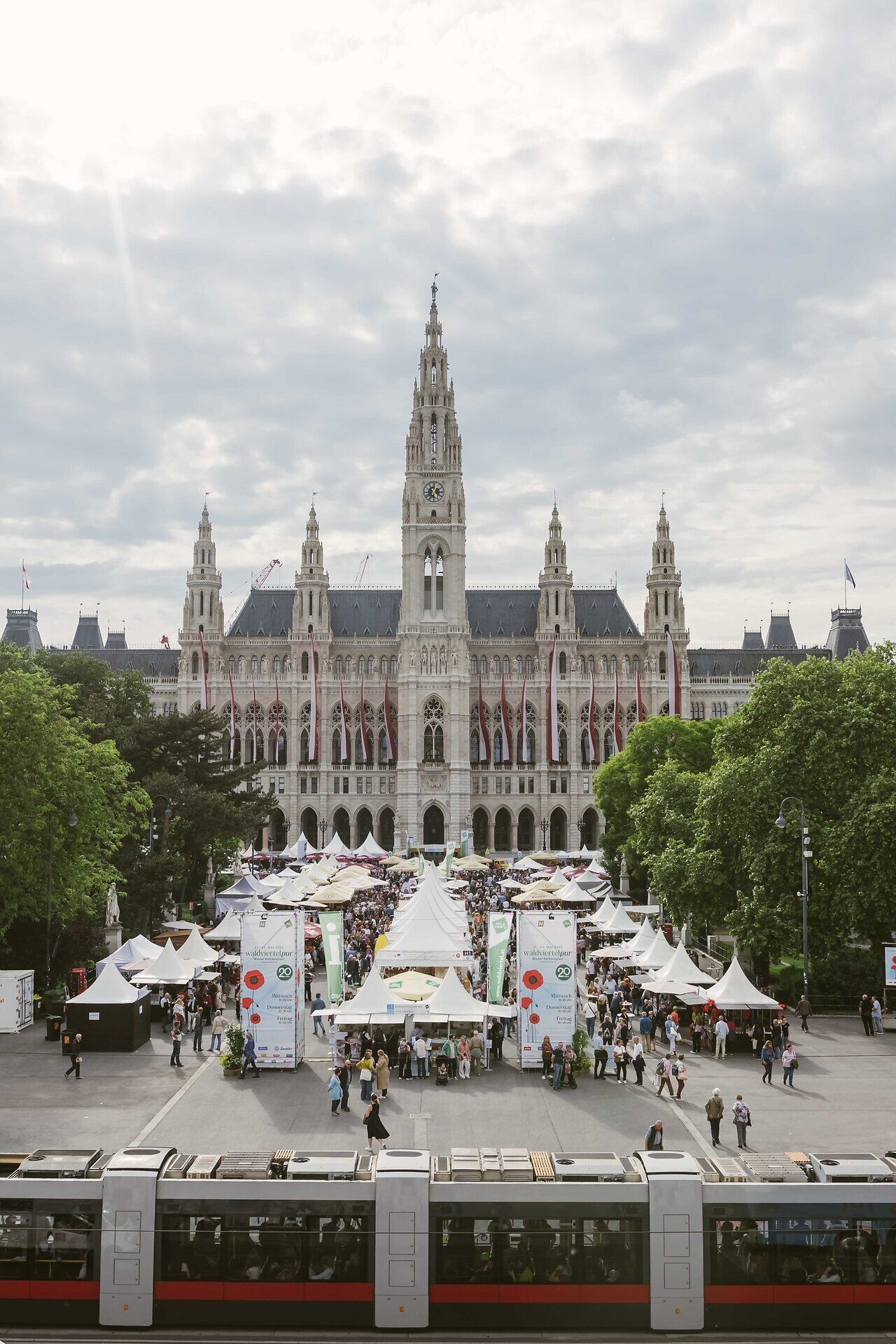 Der Wiener Rathausplatz mit Zelten und Personen während waldviertelpur, im Vordergrund fährt gerade eine Straßenbahn vorbei