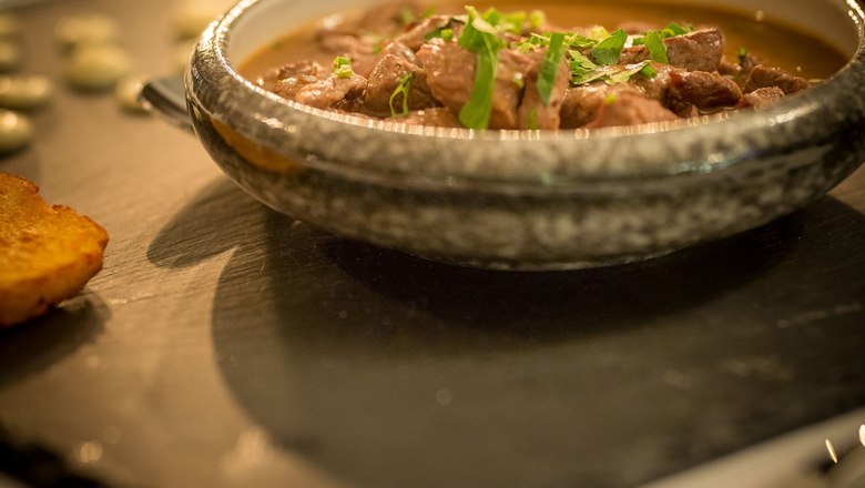 Ein Schokovulkan-Dessert auf einer Schieferplatte mit einer Kugel Eis und roten Rosenblättern dekoriert.