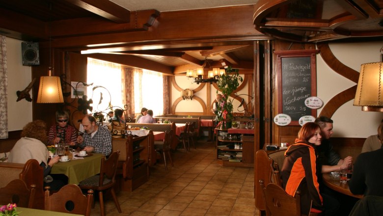 Gemütliches Restaurant mit Holzmöbeln und Gästen an Tischen.