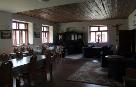 Ein gemütlicher Raum mit Holztischen, Stühlen und Sofas, dekoriert mit Teppichen und Bildern an den Wänden.