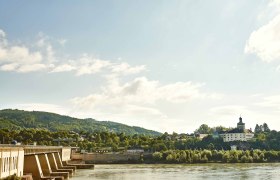 Kraftwerk Ybbs-Persenbeug an einem sonnigen Tag mit Fluss und bewaldeten Hügeln im Hintergrund.