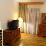 Ein Wohnzimmer mit Holzmöbeln, einem alten Fernseher, einer Stehlampe und Vorhängen.