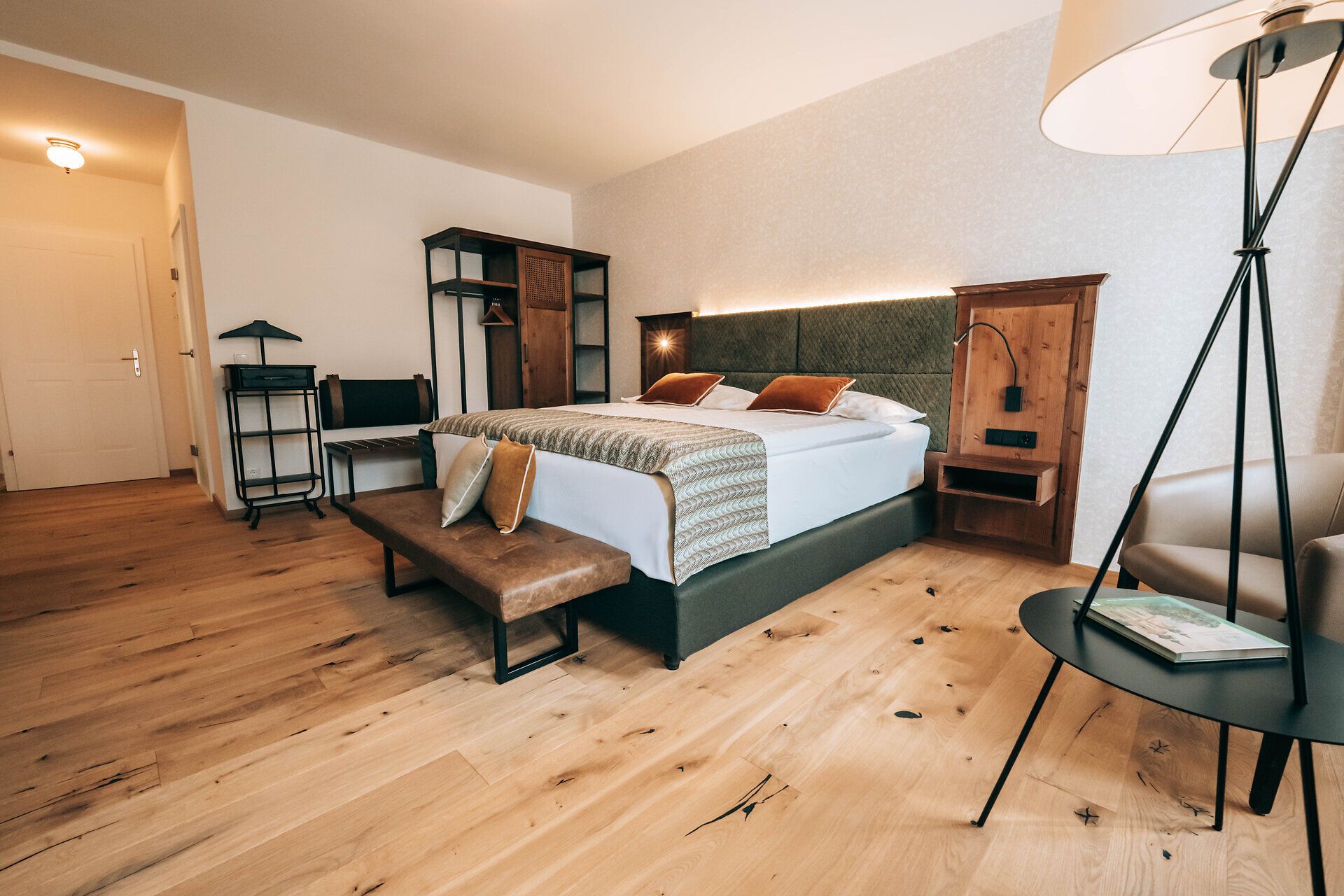 Modern eingerichtetes Hotelzimmer mit Doppelbett, Holzboden und stilvollen Möbeln.
