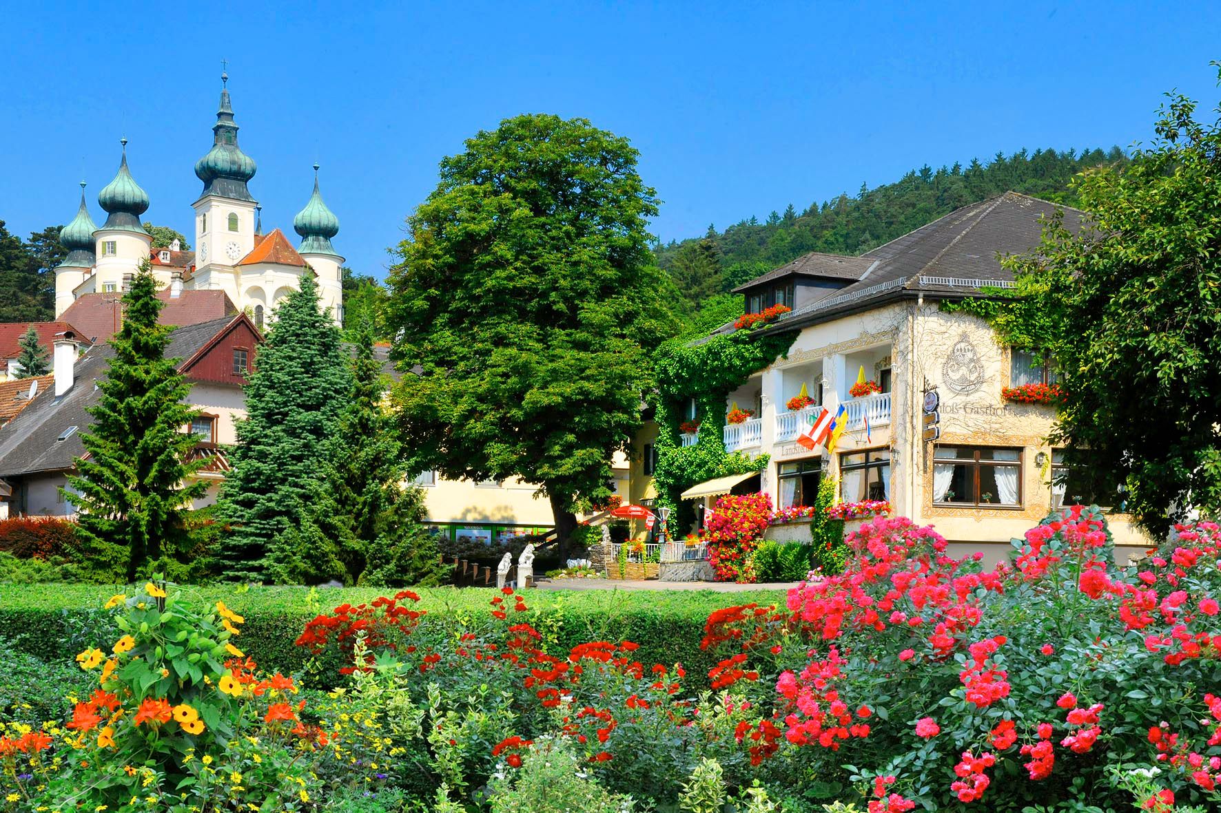 Ein malerisches Hotel mit bunten Blumen im Vordergrund und einem Schloss im Hintergrund.