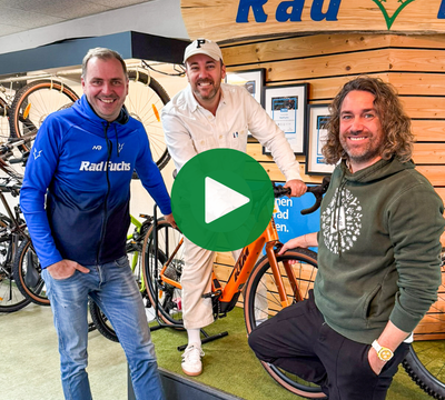 3 Personen, eine davon auf einem Fahrrad lachend in die Kamera