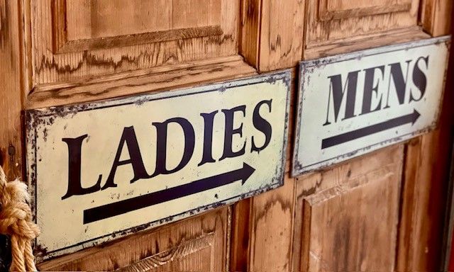 Schilder für Damen- und Herrentoilette an Holztüren.