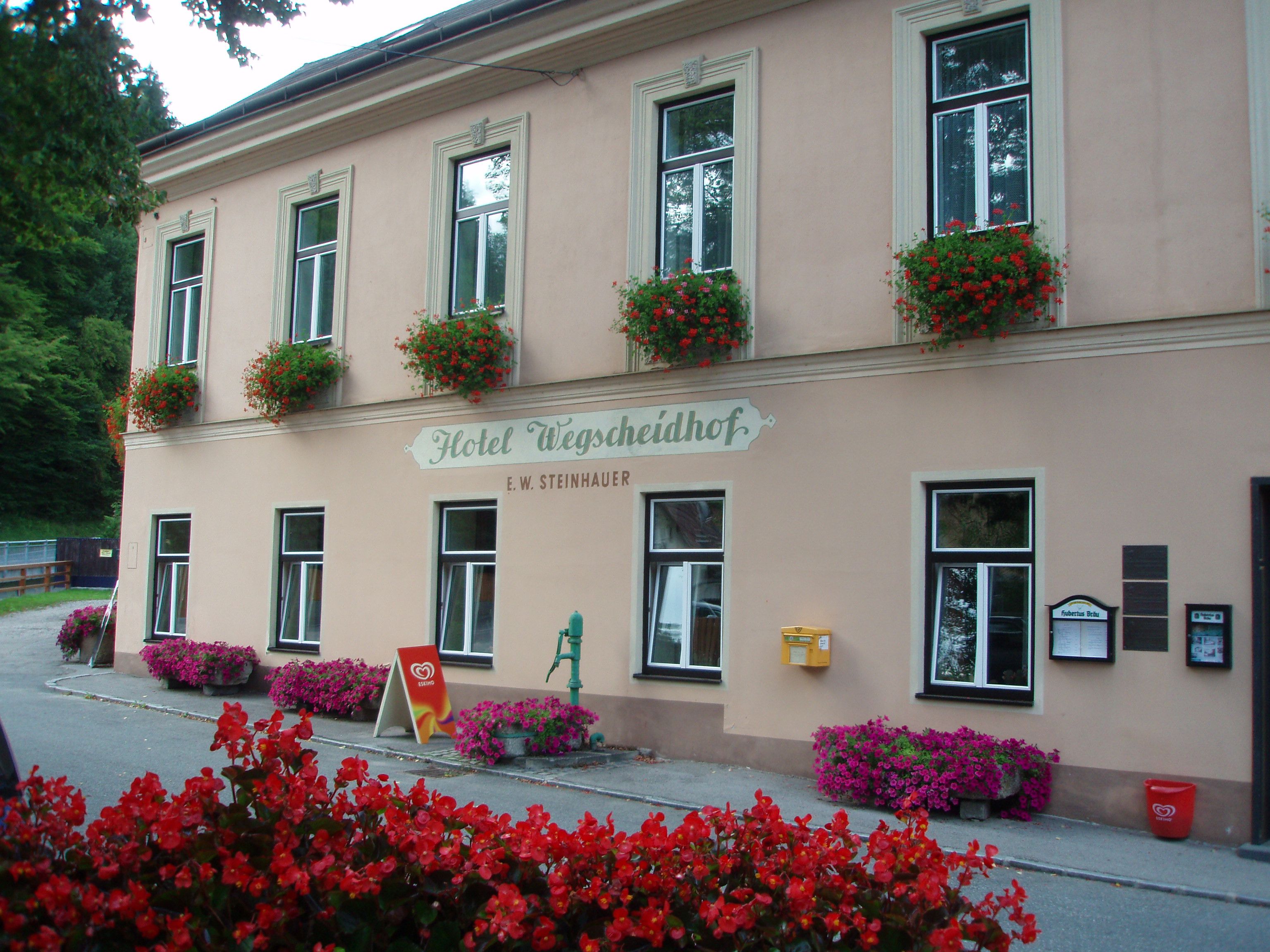 Fassade des Hotels Wegscheidhof mit Blumenkästen und Schildern.