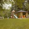 Ein Spielplatz mit Schaukel, Rutsche und Pavillon in einem grünen Garten.