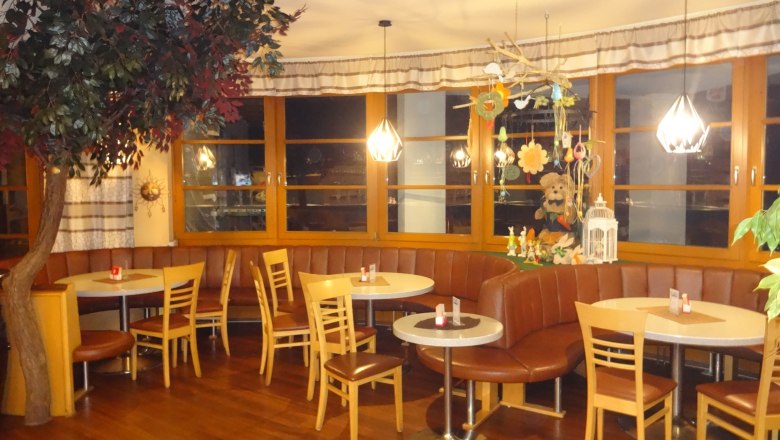 Gemütliches Café mit Holzmöbeln, Dekorationen und Pflanzen.