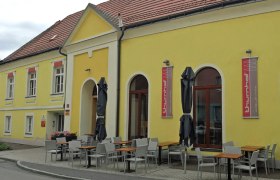 Gelbes Gebäude mit Terrasse und Tischen vor der Weinbar Thurnhof in Horn.