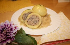 Ein Teller mit Waldviertler Fleischknödeln auf Sauerkraut, dekoriert mit einer Blume.