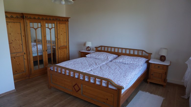 One bedroom with a wooden double bed, a closet with mirrors and two bedside tables with lamps.