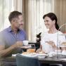 A smiling couple having breakfast at a table with coffee and orange juice.