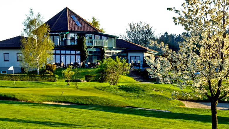 Clubhaus des Golfclubs Ottenstein mit bl&uuml;hendem Baum im Vordergrund.
