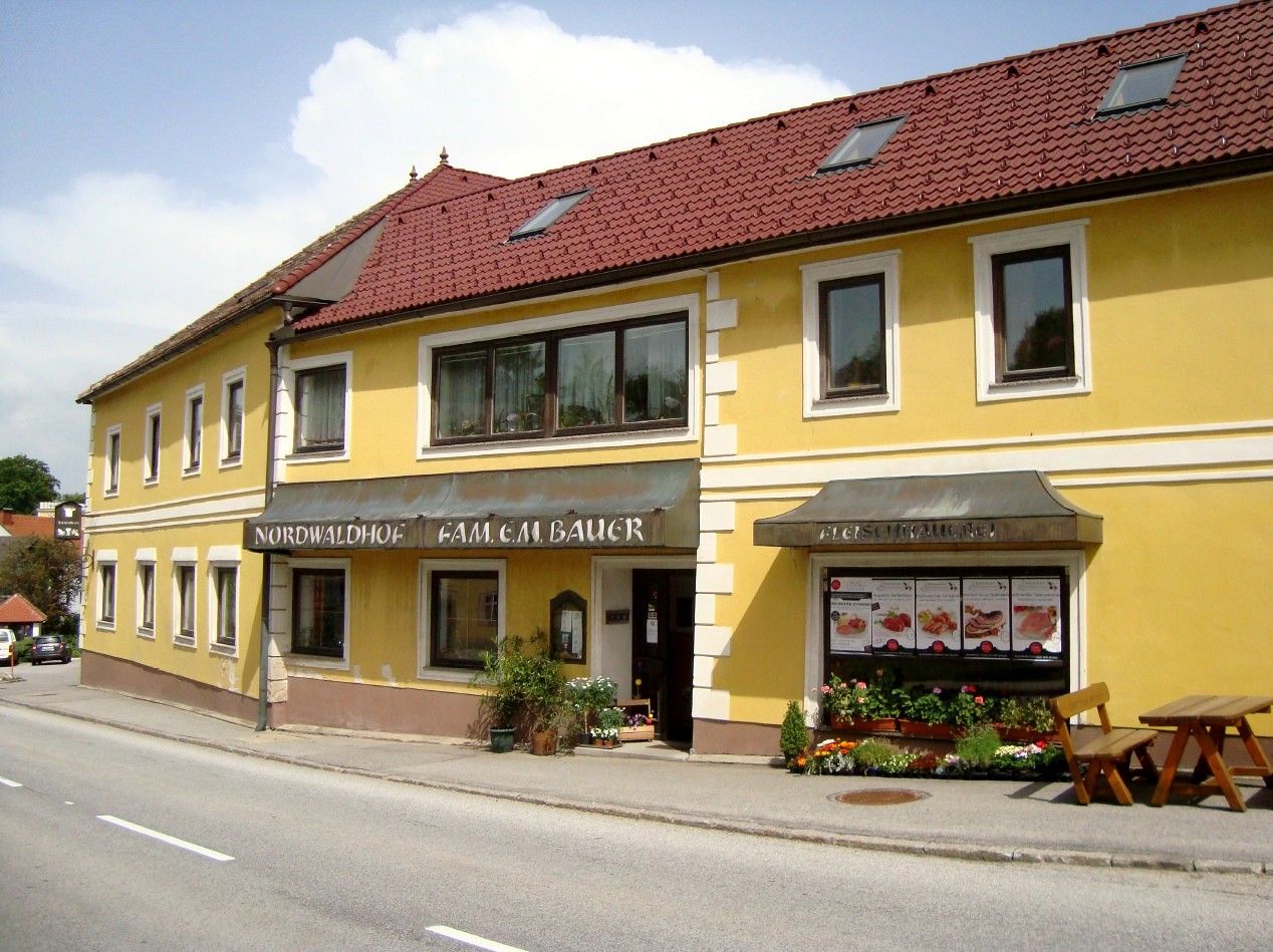 Gelbes Gebäude mit rotem Dach und Schildern 'Nordwaldhof' und 'Fleischhauerei'.