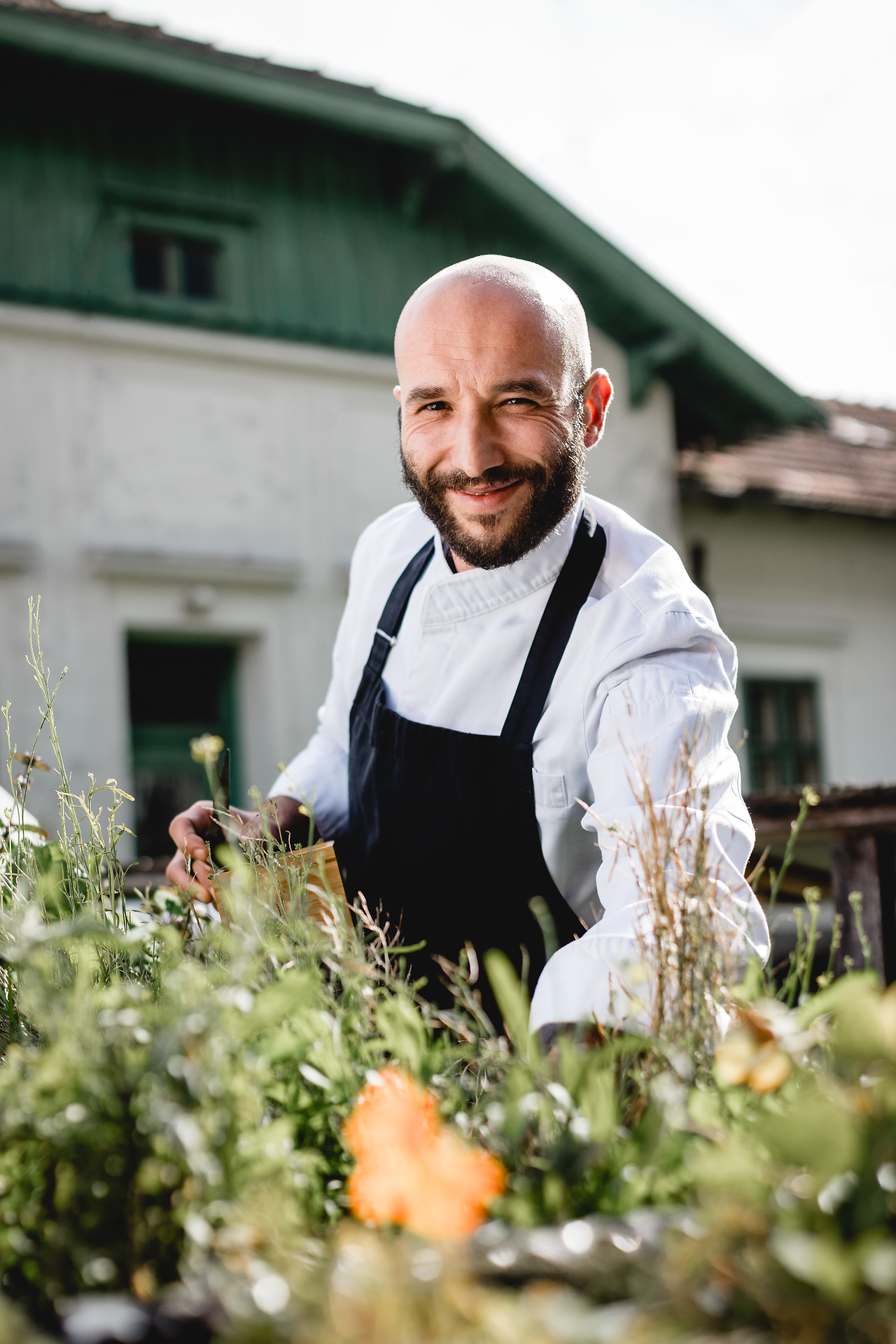 Inmitten eines blühenden Gartens strahlt der Wirt mit einem herzlichen Lächeln, während er frische Kräuter erntet. Die sanfte Brise und die warmen Sonnenstrahlen schaffen eine einladende Atmosphäre, die zum Verweilen einlädt. Hier wird die Wirtshauskultur lebendig und verspricht unvergessliche Genussmomente.