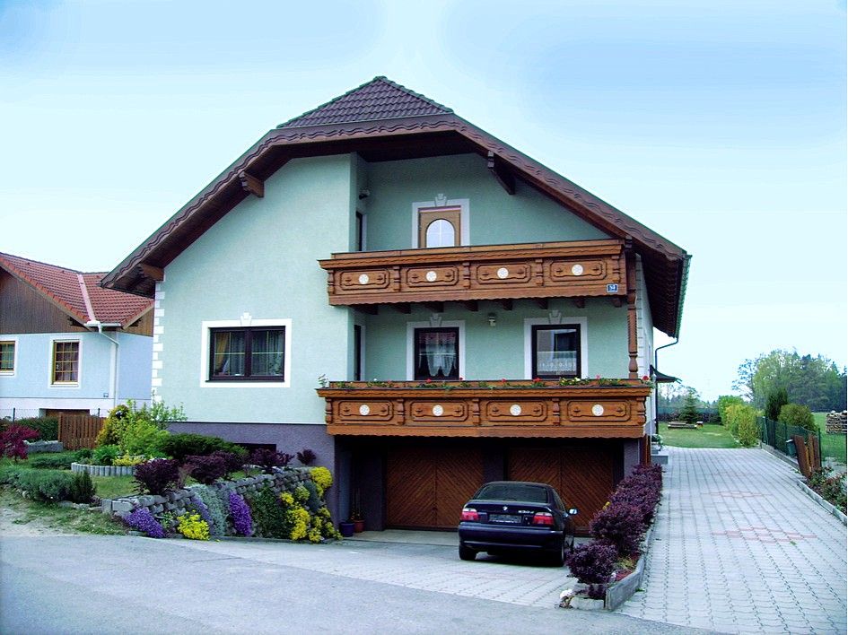 Ein zweistöckiges Haus mit Holzbalkon und Garten.