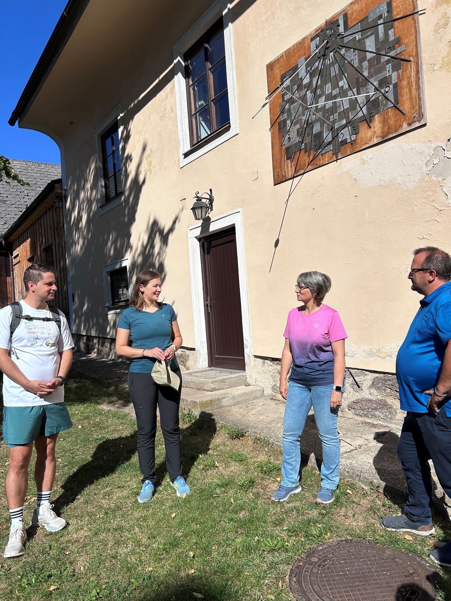 4 Personen im Halbkreis in einem Hof