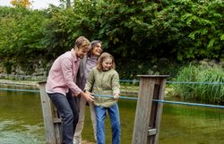 Eine Familie genießt einen unbeschwerten Moment auf einem kleinen Floß, umgeben von der idyllischen Natur der Erlebnisgärten. Die Kinder lachen und erkunden die Umgebung, während die sanften Wellen des Wassers eine friedliche Atmosphäre schaffen.