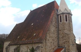 Pfarrkirche Pöbring mit steilem Dach und Turm vor blauem Himmel.