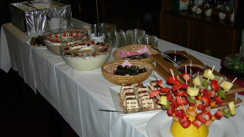 Buffet mit Desserts und Obstspießen auf einem Tisch.