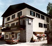 Ein zweistöckiges Gebäude mit Balkon und Terrasse, beschriftet mit 'Steinbrunner'.