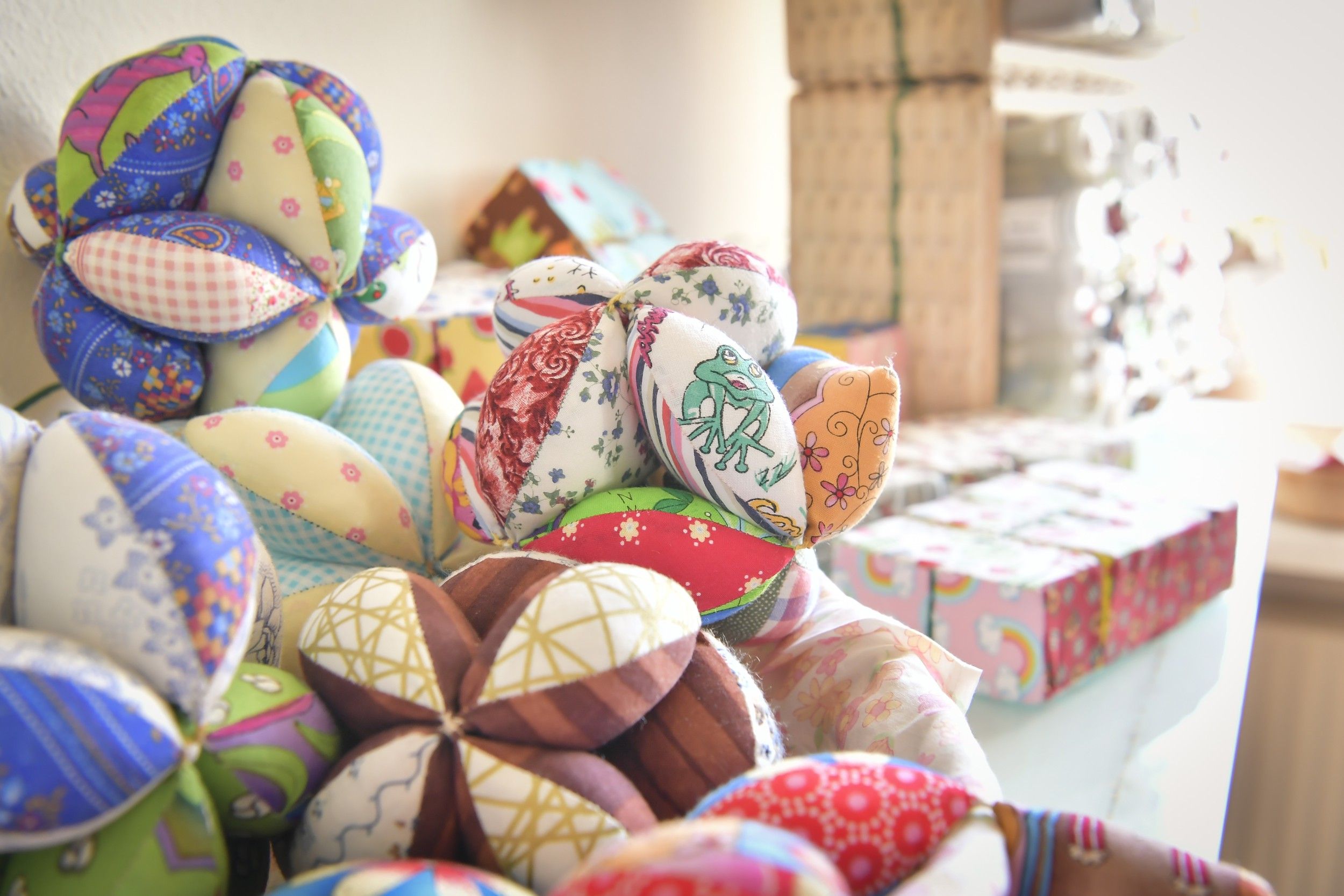 Bunte, handgefertigte Stoffbälle in verschiedenen Mustern und Farben auf einem Tisch.