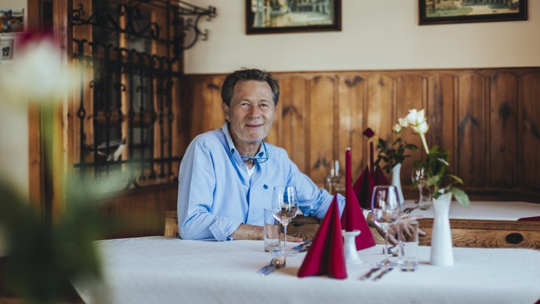 Karlheinz Ringl sitzt an einem gedeckten Tisch in seinem Gasthaus.