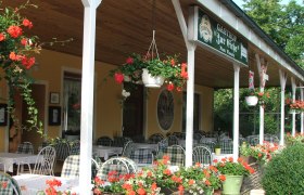 Außenbereich eines Gasthofs mit Tischen und Blumen.