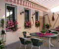 Cozy outdoor area of an inn with tables, chairs and flowers.