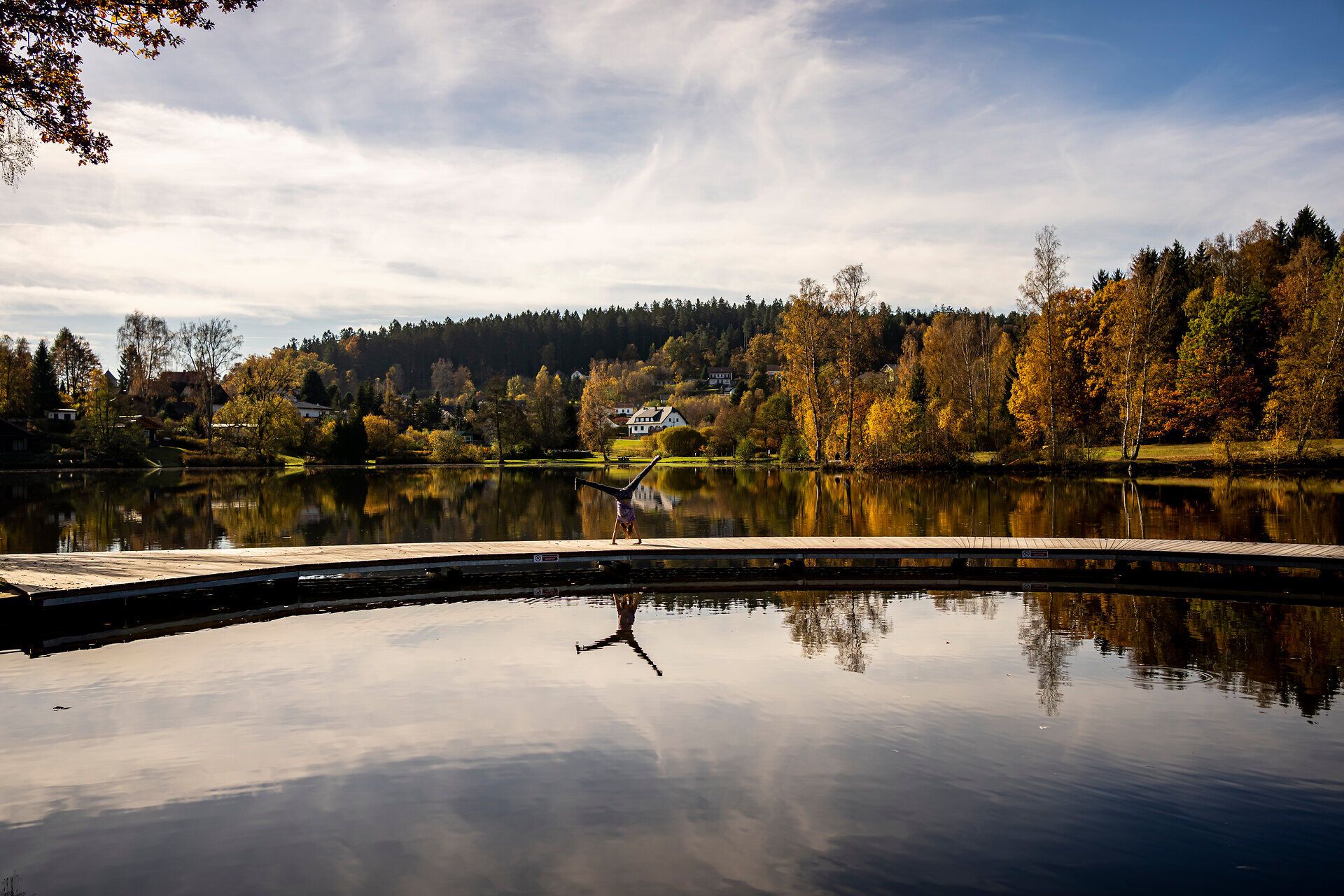Die sanften Hügel spiegeln sich im ruhigen Wasser, während die bunten Blätter der Bäume im goldenen Licht des Herbstes leuchten. Ein Ort der Ruhe und Erholung, wo die Natur ihre schönsten Farben entfaltet und die Seele zur Ruhe kommt.