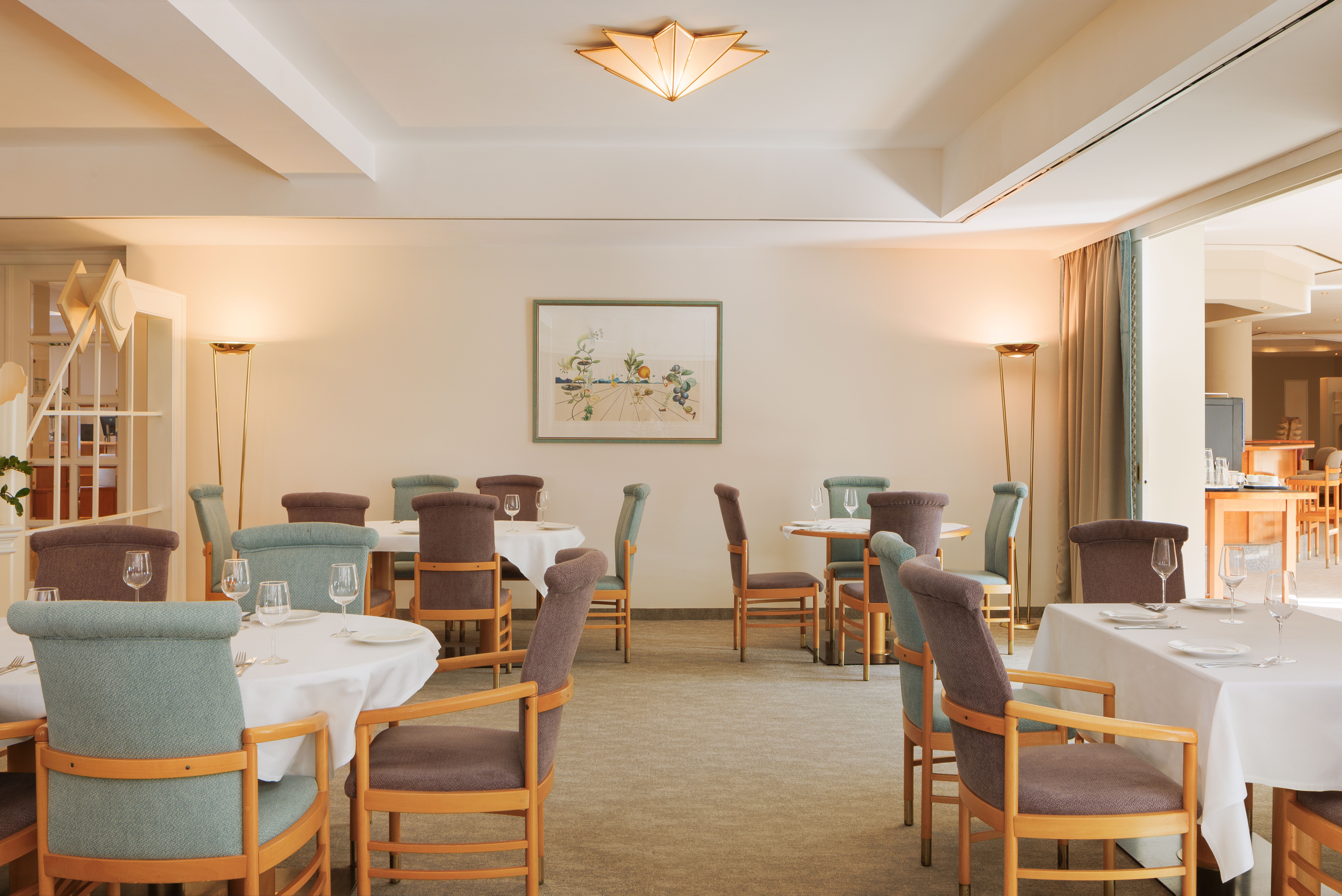 Elegantes Restaurant mit gedeckten Tischen und gepolsterten Stühlen.