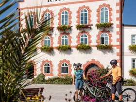 Die malerische Kulisse des Rathauses in Waidhofen l&auml;dt Radfahrer dazu ein, eine wohlverdiente Pause einzulegen. Bunte Blumenbeete umrahmen den Platz und schaffen eine einladende Atmosph&auml;re, die den Sommer in den Bergen perfekt widerspiegelt.