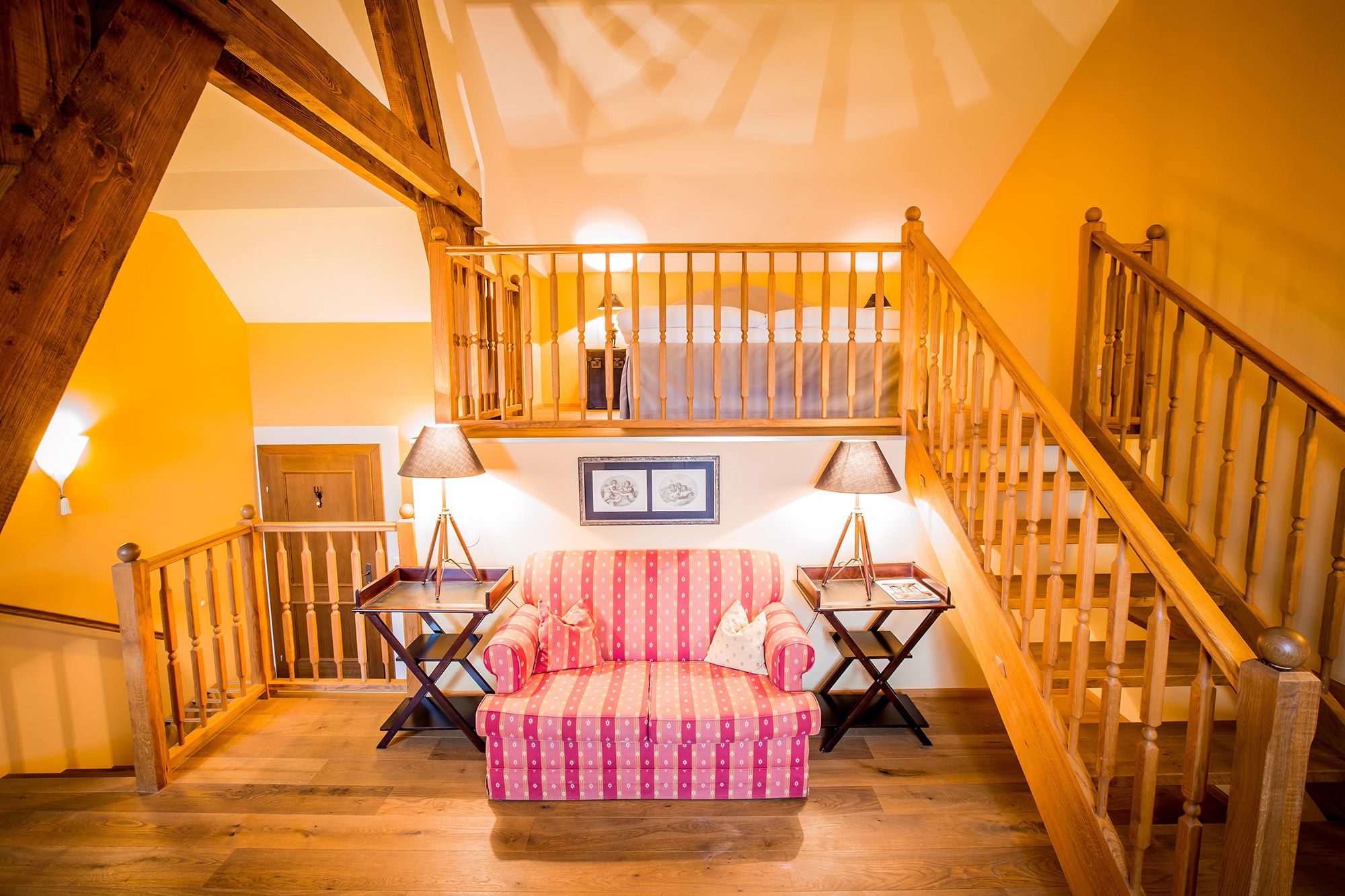 Gemütliche Suite mit Holzbalken, Treppe, Sofa und Lampen.