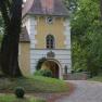 Historisches Gebäude mit Turm und Uhr in einem Waldgebiet.