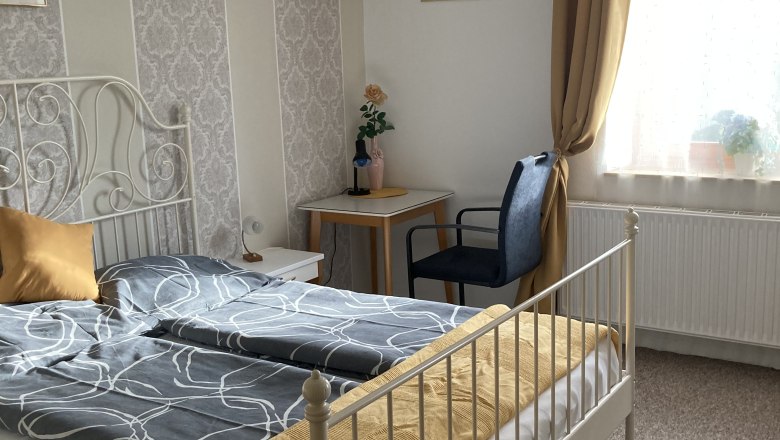 Gemütliches Schlafzimmer mit Doppelbett, gelben Vorhängen und dekorativer Tapete.