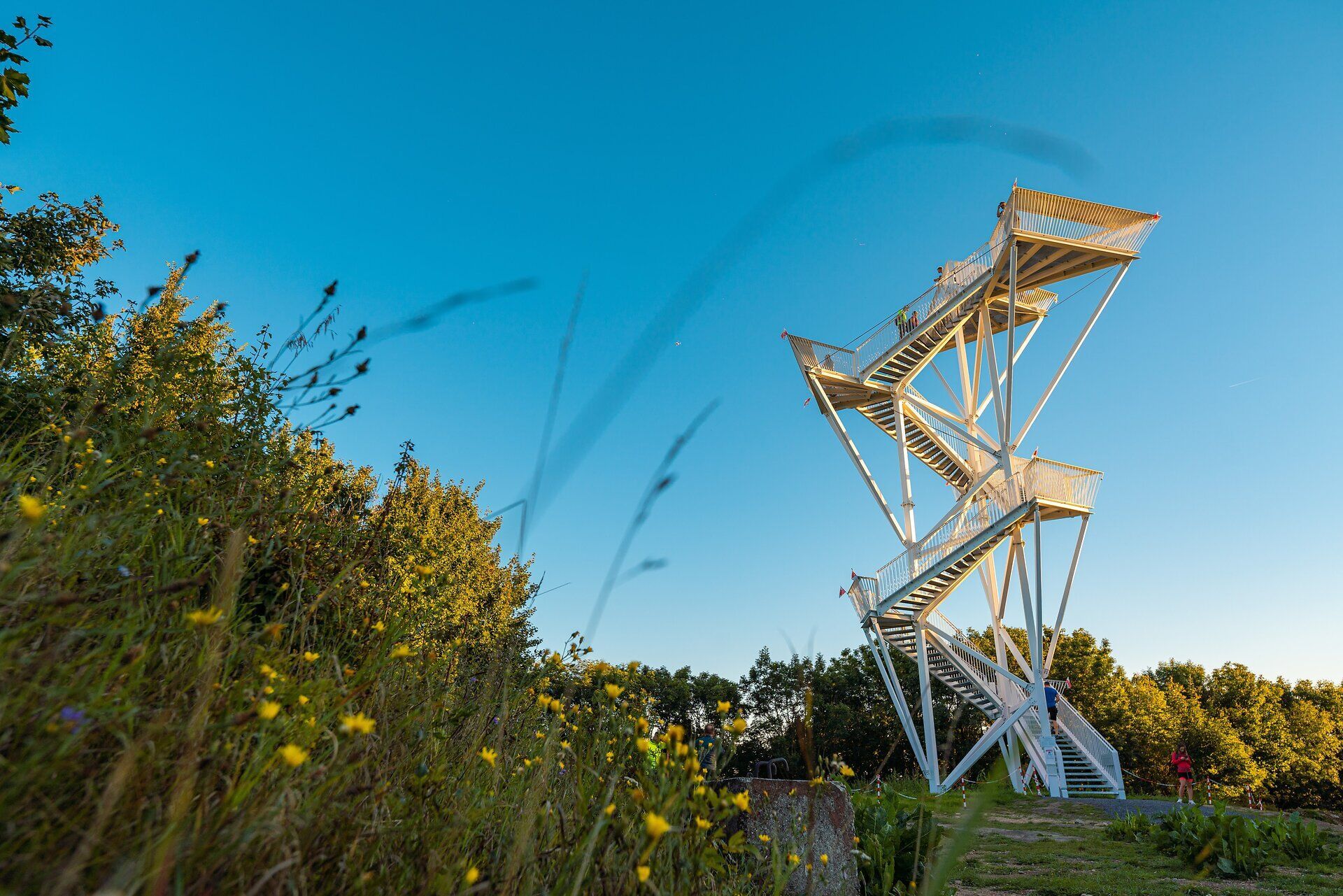 Der Aussichtsturm erhebt sich majestätisch über die umliegende Landschaft und bietet einen atemberaubenden Blick auf die sanften Hügel und dichten Wälder. Die frische Bergluft und das Zwitschern der Vögel schaffen eine einladende Atmosphäre für Wanderer und Naturliebhaber. Ein perfekter Ort, um die Schönheit der Natur in vollen Zügen zu genießen.