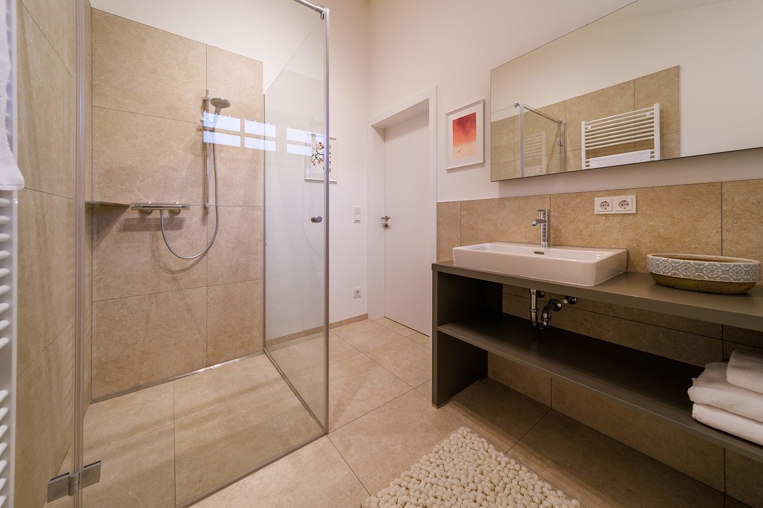 Modernes Badezimmer mit begehbarer Dusche, Waschbecken und großem Spiegel.