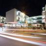 Night shot of a modern building complex with glass façade and illuminated interiors.