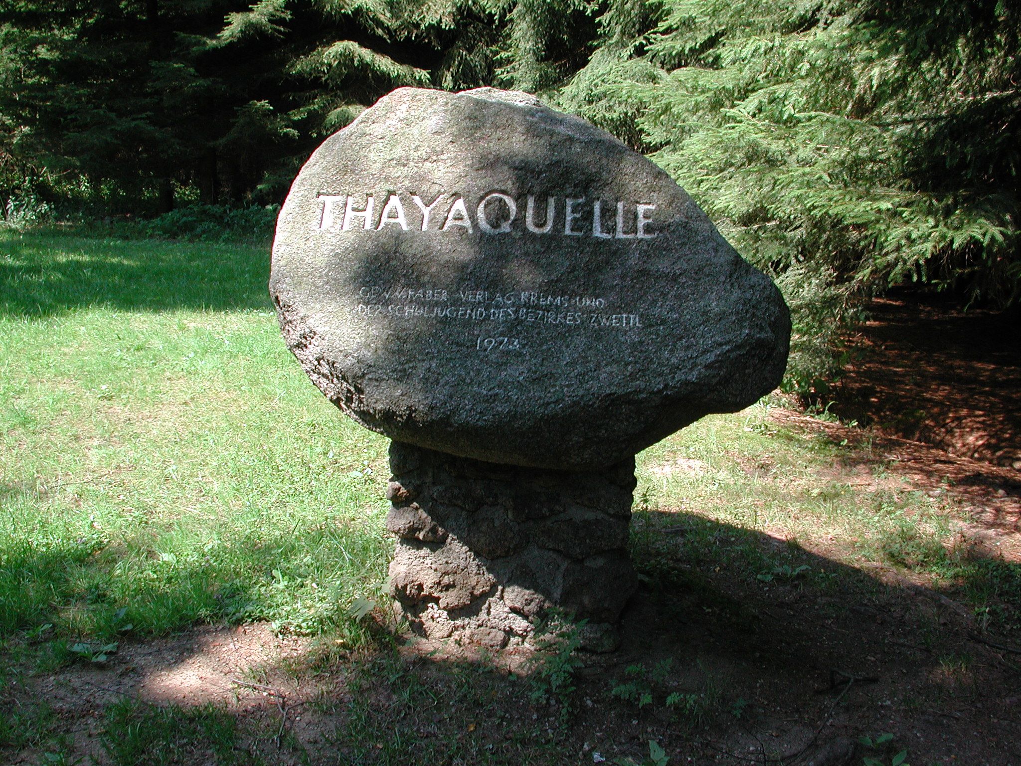 Ein Gedenkstein mit der Aufschrift 'Thayaquelle' im Wald.