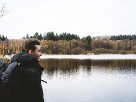 Ein stiller Moment am Teichwanderweg, wo die sanften Wellen des Wassers die umliegenden B&auml;ume spiegeln. Die k&uuml;hle Winterluft umh&uuml;llt die Szenerie und l&auml;dt zu einem besinnlichen Spaziergang ein, w&auml;hrend die Natur in ihrer winterlichen Pracht erstrahlt.