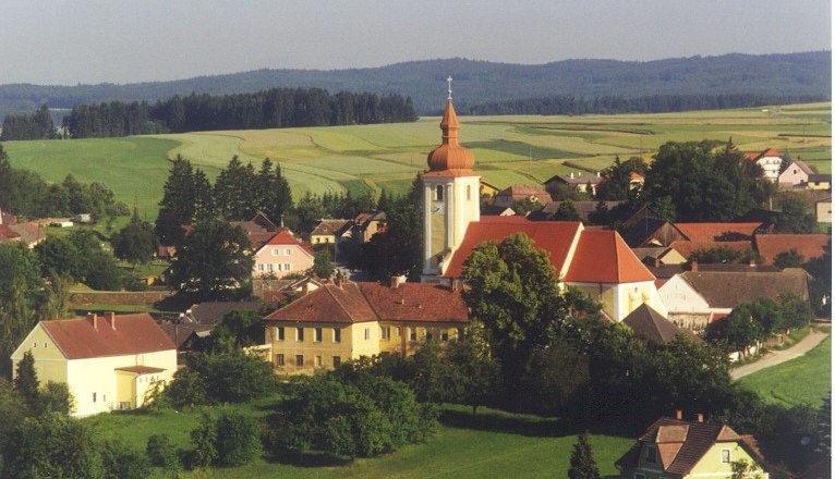 Luftaufnahme von Waldkirchen an der Thaya mit Kirche und umliegenden Häusern, umgeben von Feldern und Wäldern.
