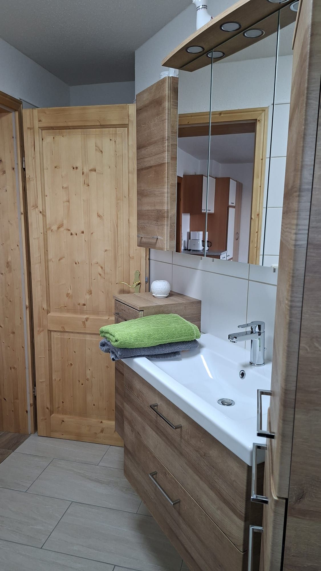 Badezimmer mit Holzschränken, Waschbecken und Handtüchern.