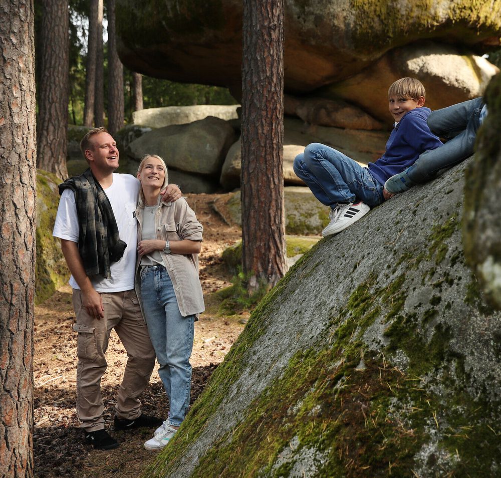 Zwei Burschen liegen auf einem großen Felsen, ihre Eltern stehen am Fuße des Felsen.